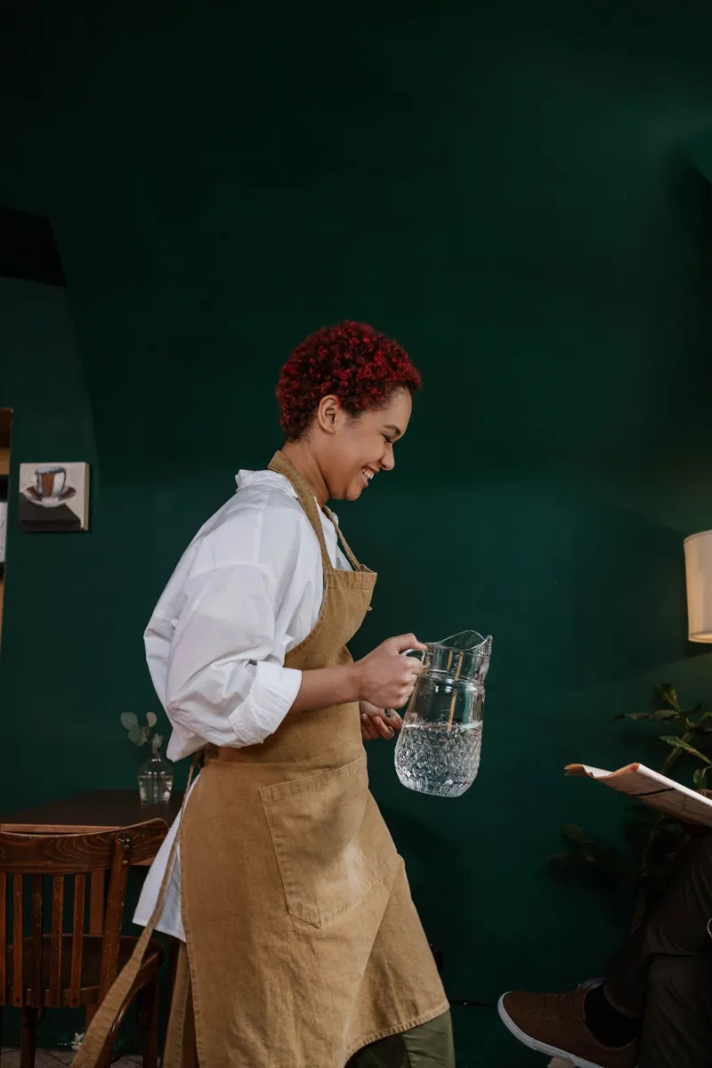 Servicekraft mit Wasserkaraffe im Gastraum